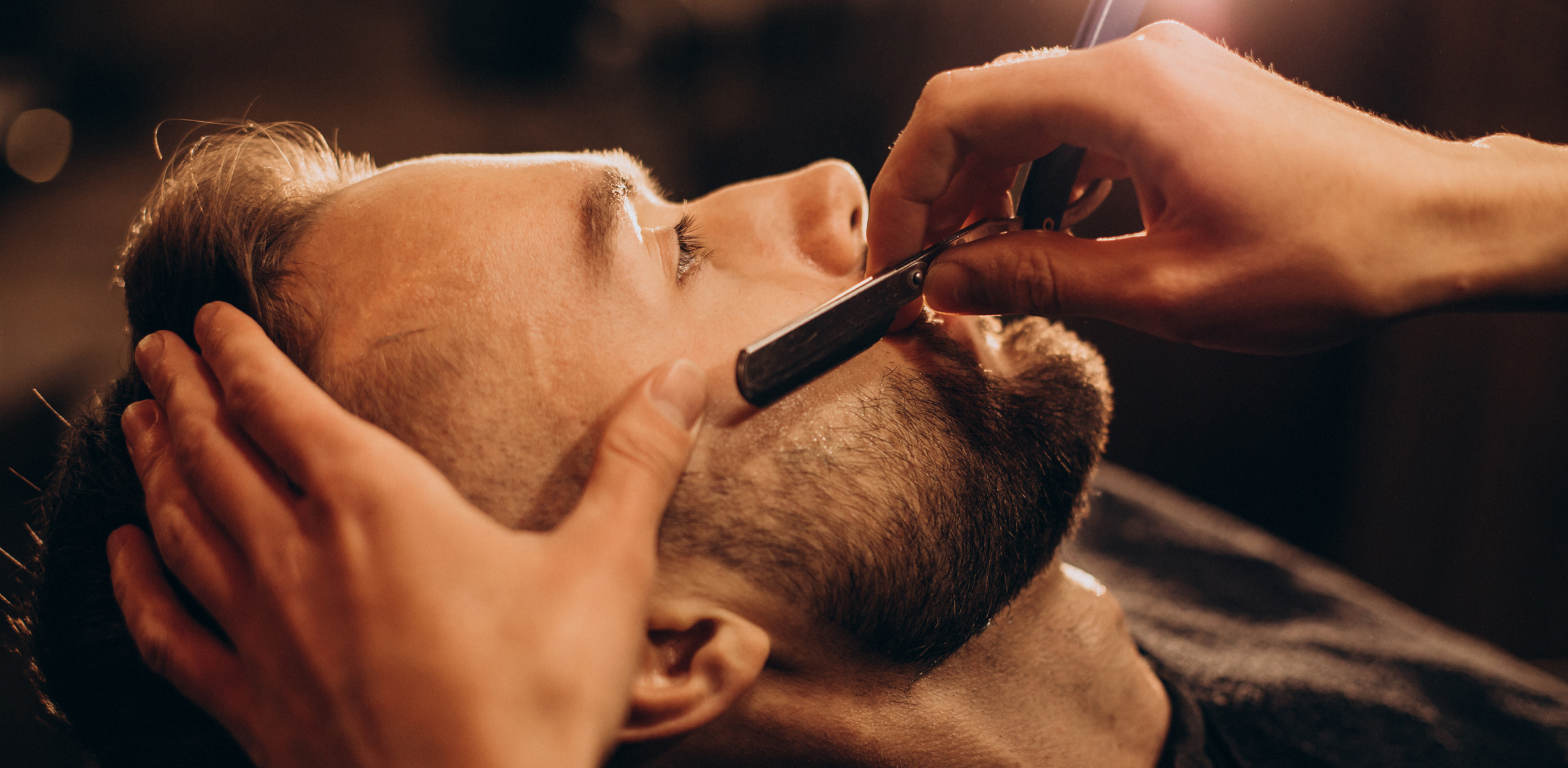 Handsome man shaving beard at barbershop